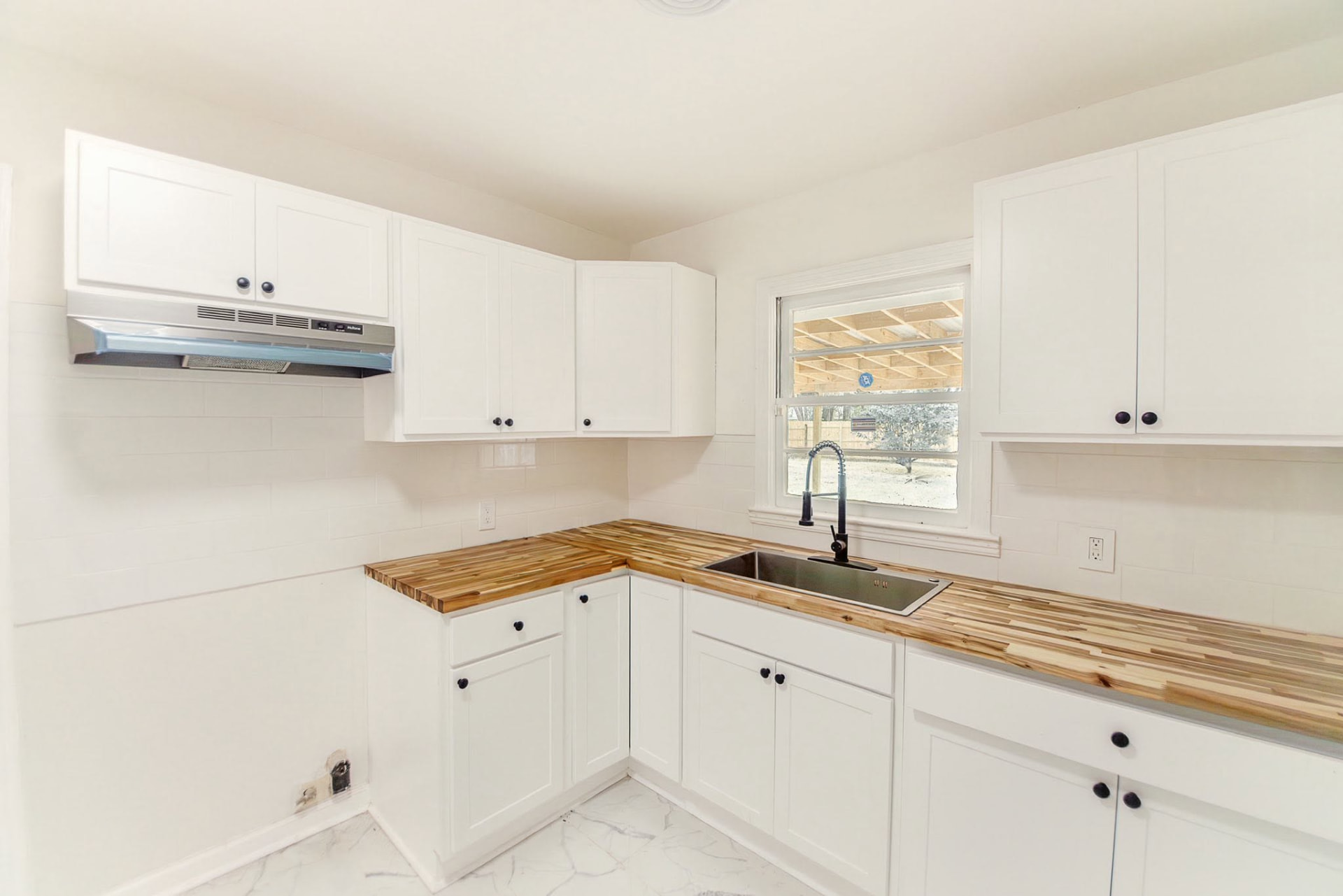 Remodeled kitchen with white shaker cabinets and butcher-block counters