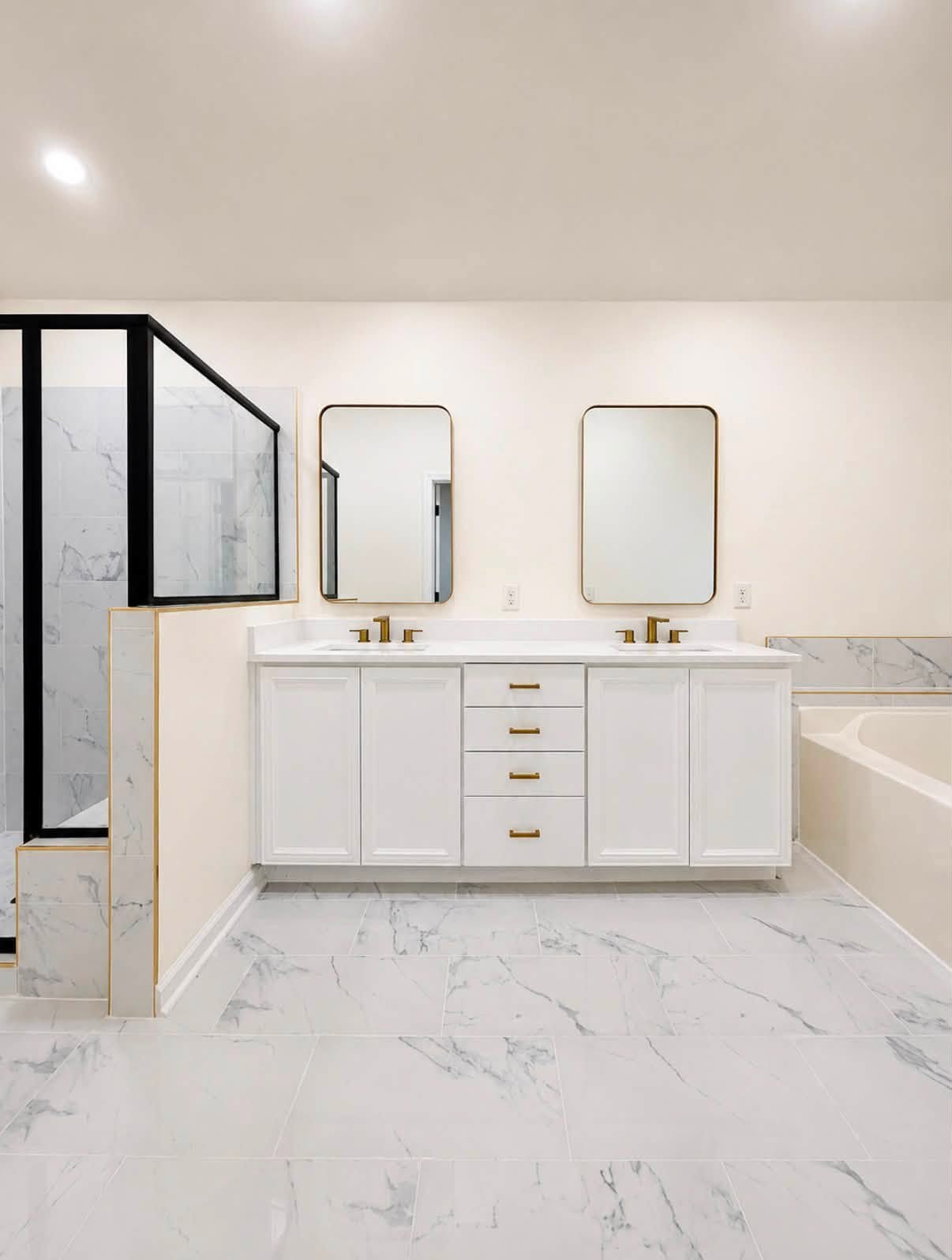 Fully remodeled primary bathroom with white double vanity, brass hardware, black-framed glass shower, and marble-look tile floor